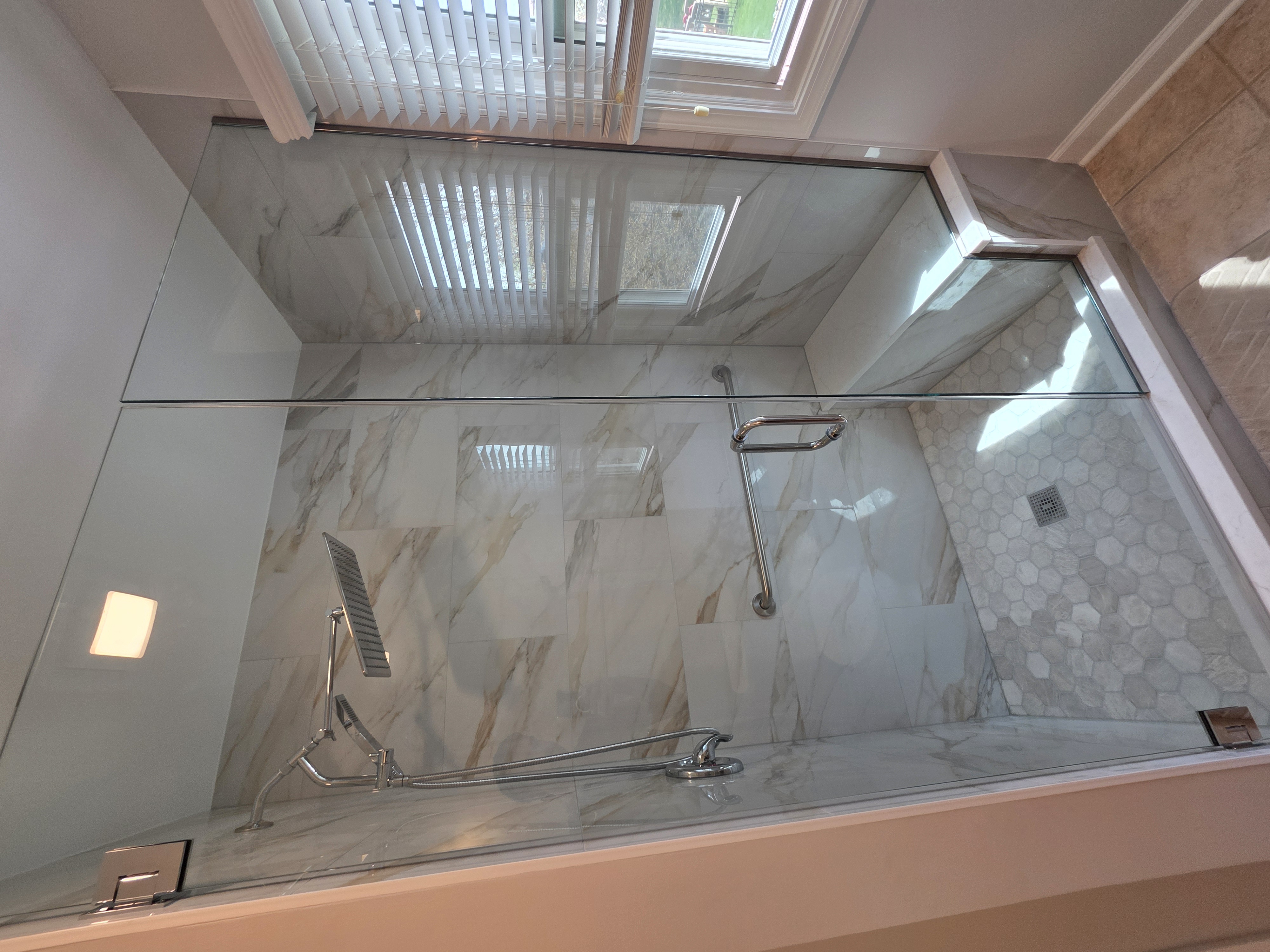 Marble shower with glass enclosure and built-in bench
